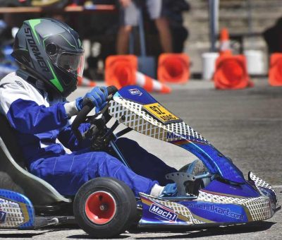 Un coureur en karting porte un casque et pilote un kart bleu sur piste