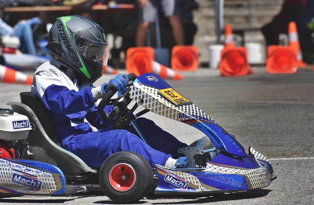 Un coureur en karting porte un casque et pilote un kart bleu sur piste