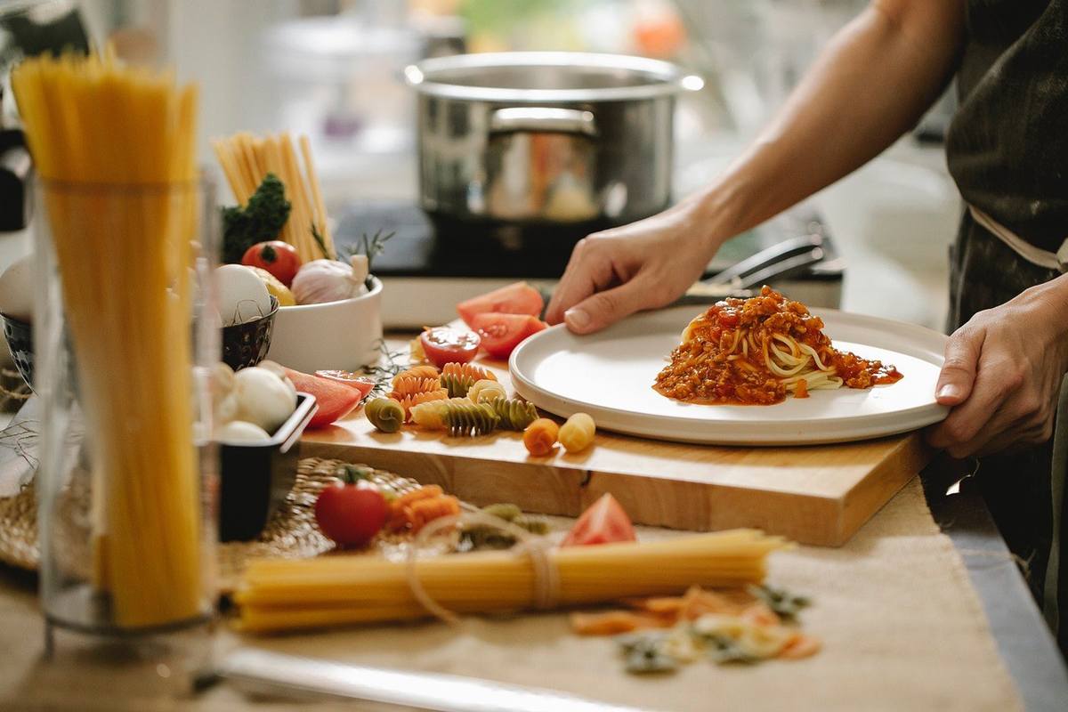 Chef assiette des pâtes sur une table de cuisine
