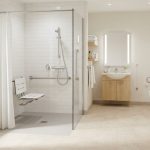 Salle de bain accessible senior, douche de plain-pied avec barre d'appui et siège, carrelage clair, lumineuse