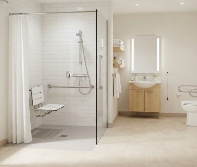 Salle de bain accessible senior, douche de plain-pied avec barre d'appui et siège, carrelage clair, lumineuse