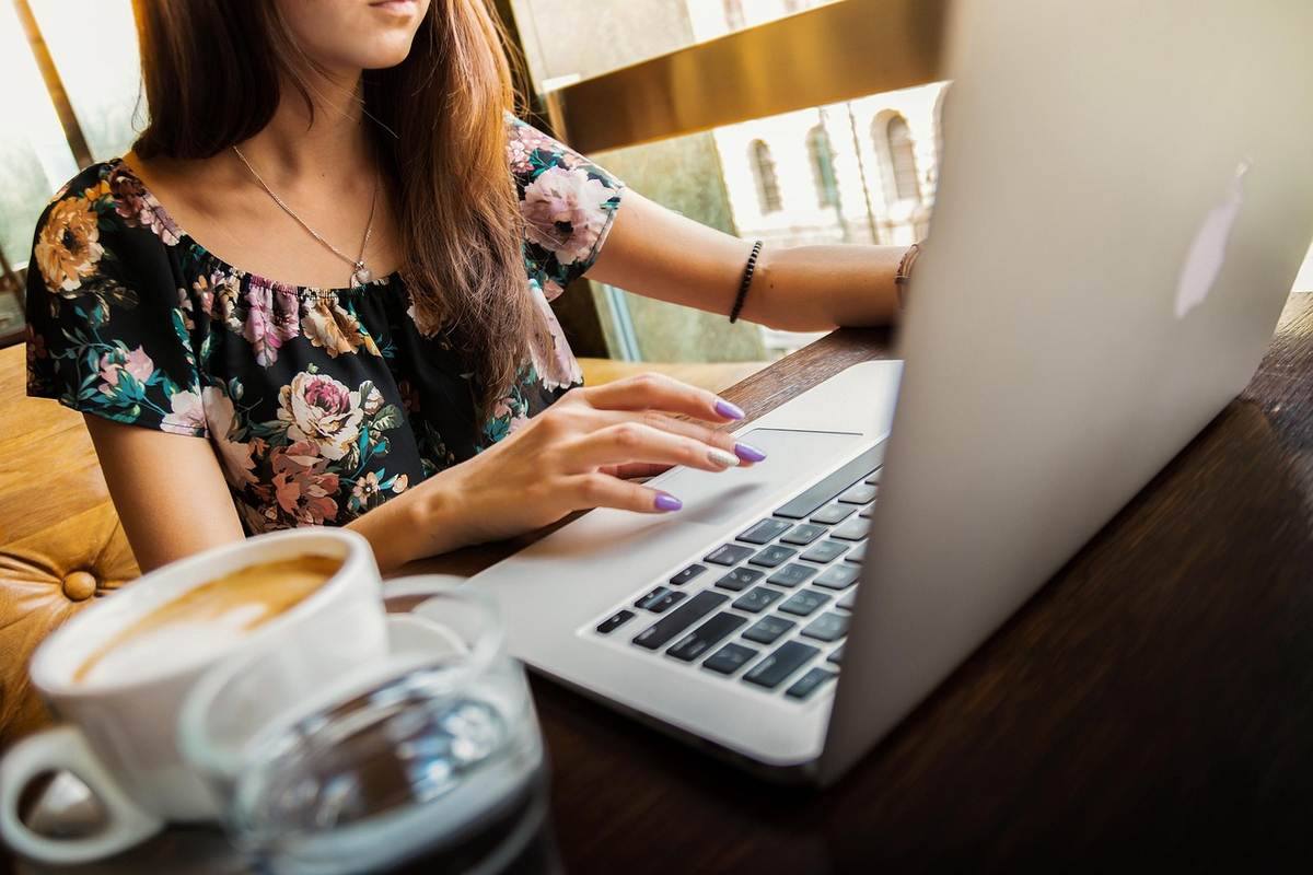 Une femme en chemise fleurie utilise un ordinateur portable à un bureau