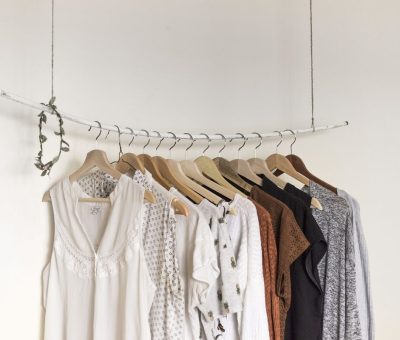 Une rangée de cintres suspendus portant des vêtements légers sur un mur blanc